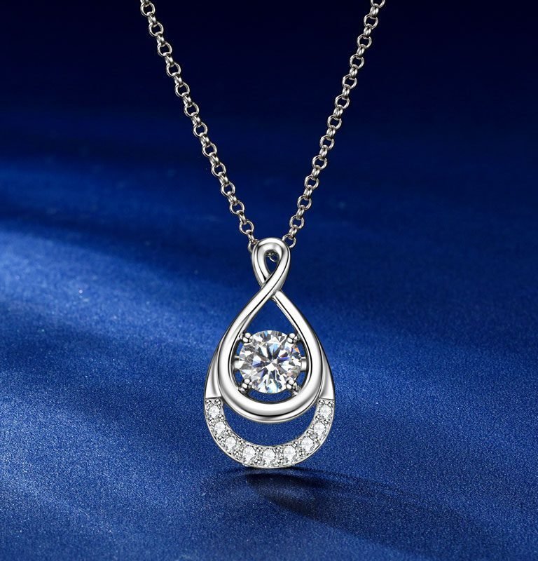 Vista frontal del collar «Elyenne» de GLAMAVERA con colgante de moissanita de 1 quilate en forma de infinito, en plata sobre fondo azul