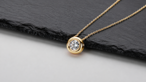 Gold-tone moissanite pendant necklace displayed on black slate in a 16:9 composition.