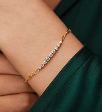 glamavera-kessane-bar-bracelet-gold-on-wrist GLAMAVERA Kessane gold-plated moissanite tennis bracelet worn on the wrist with an elegant green sleeve