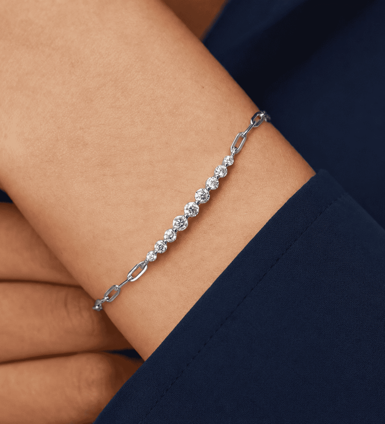 Pulsera «Kessane Bar» de GLAMAVERA, en plata de ley 925, lucida en la muñeca con una manga azul marino
