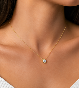glamavera-velrose-droplet-necklace-gold-model Velrose Droplet Necklace in gold finish worn by a model, featuring a round brilliant moissanite pendant in 925 sterling silver.