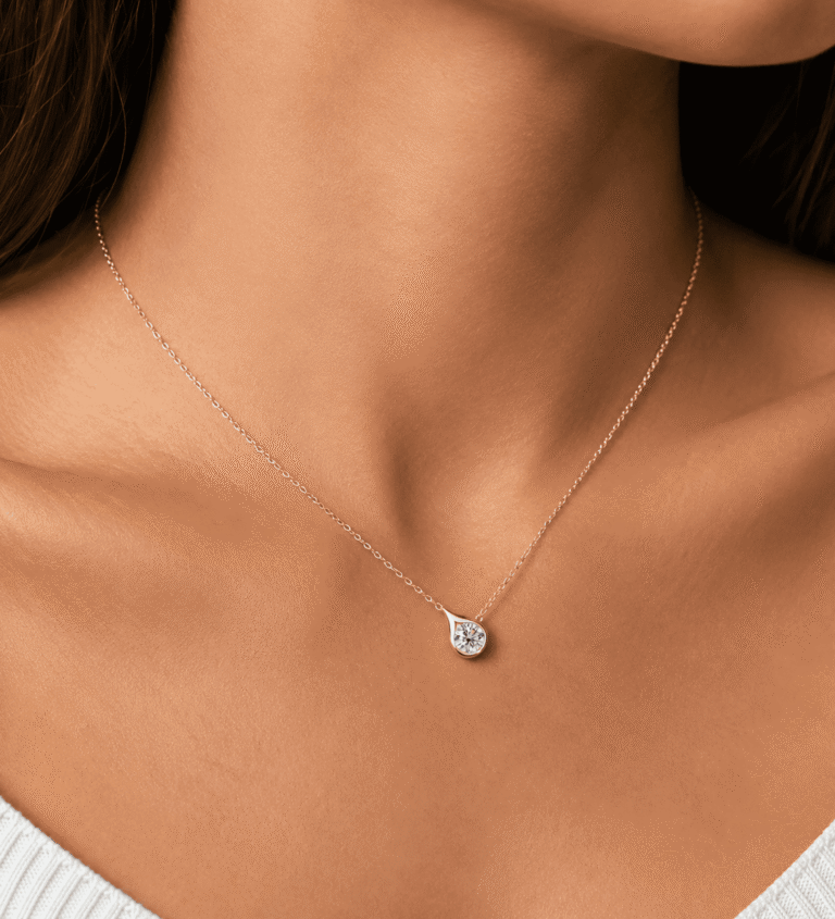 Collar «Velrose Droplet» con acabado dorado, lucido por una modelo, con un colgante de moissanita redonda brillante en plata de ley 925.