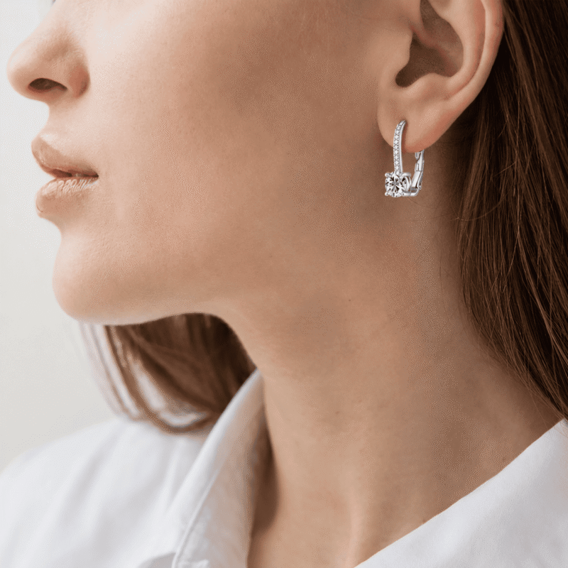 rivane-drops-silver-moissanite-earrings-on-ear Close-up of a woman wearing Rivane Drops moissanite leverback earrings in 925 sterling silver