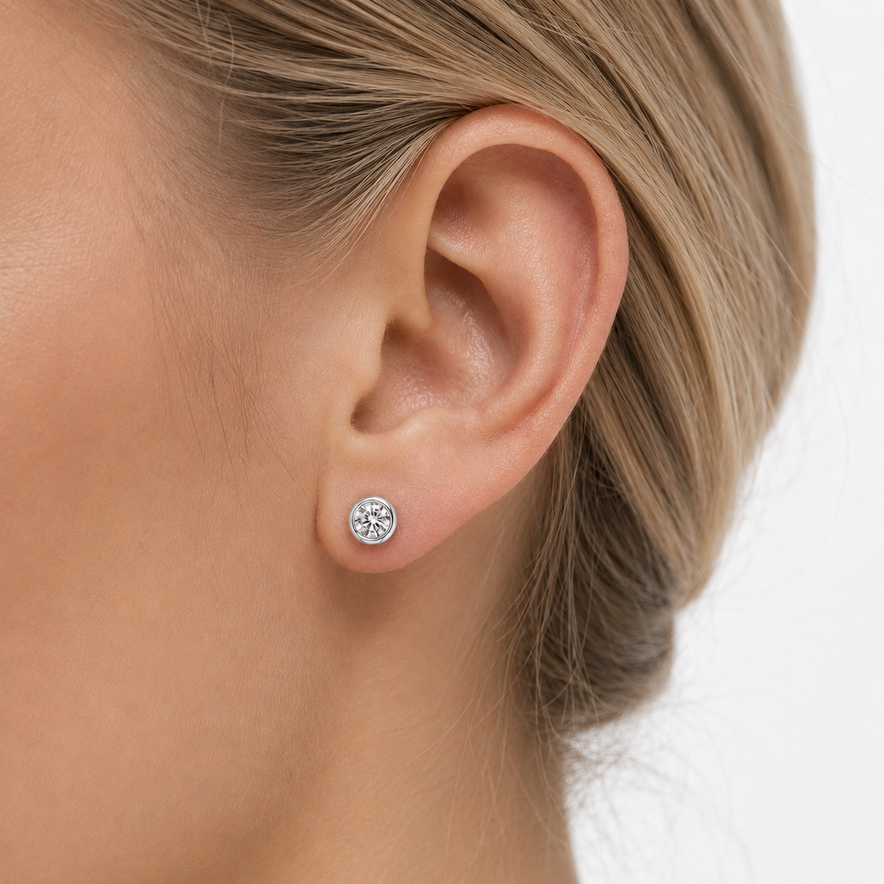 Silver moissanite stud earrings worn on the ear